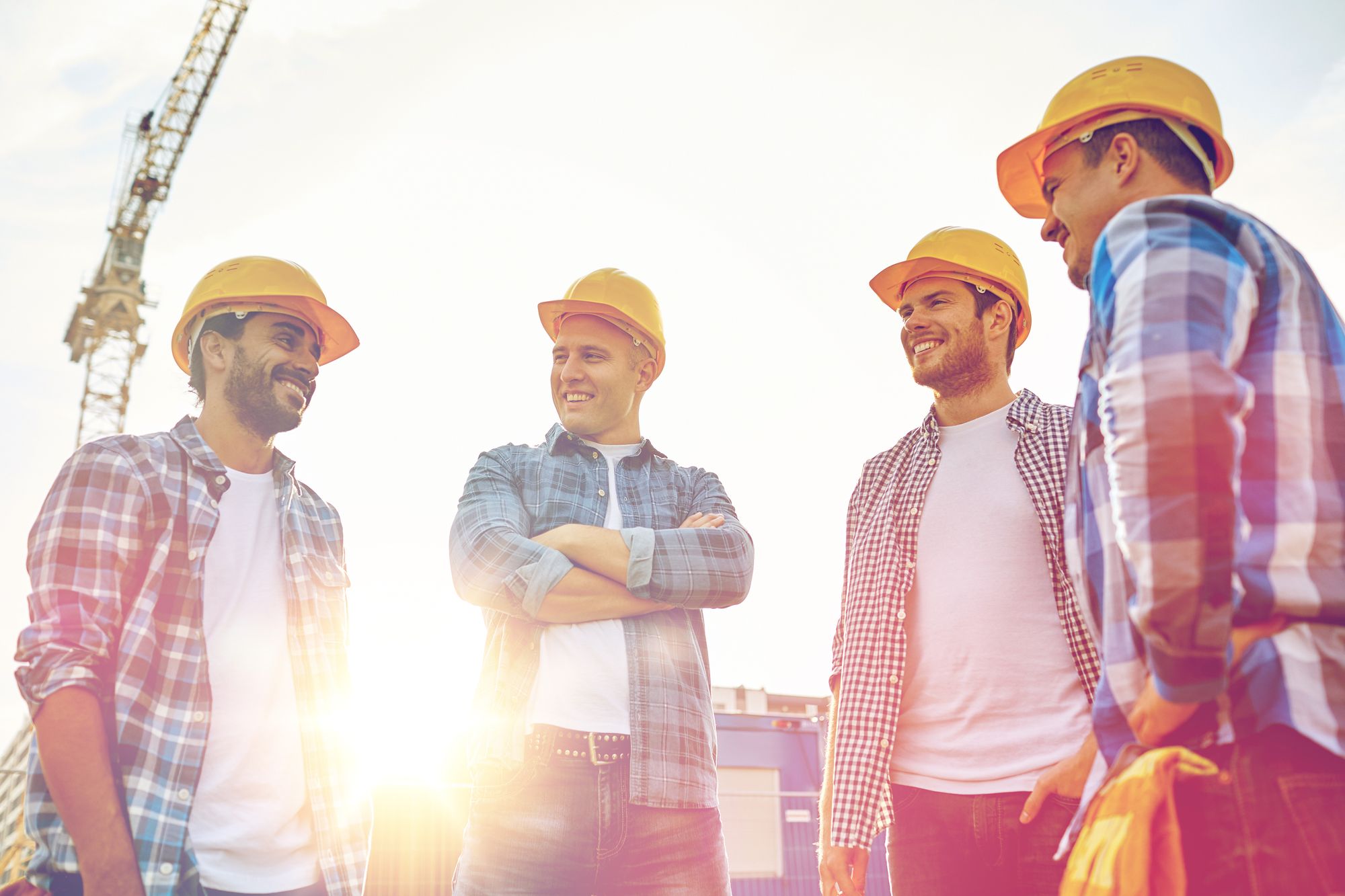 A crew in hard hats talking on site at sunrise