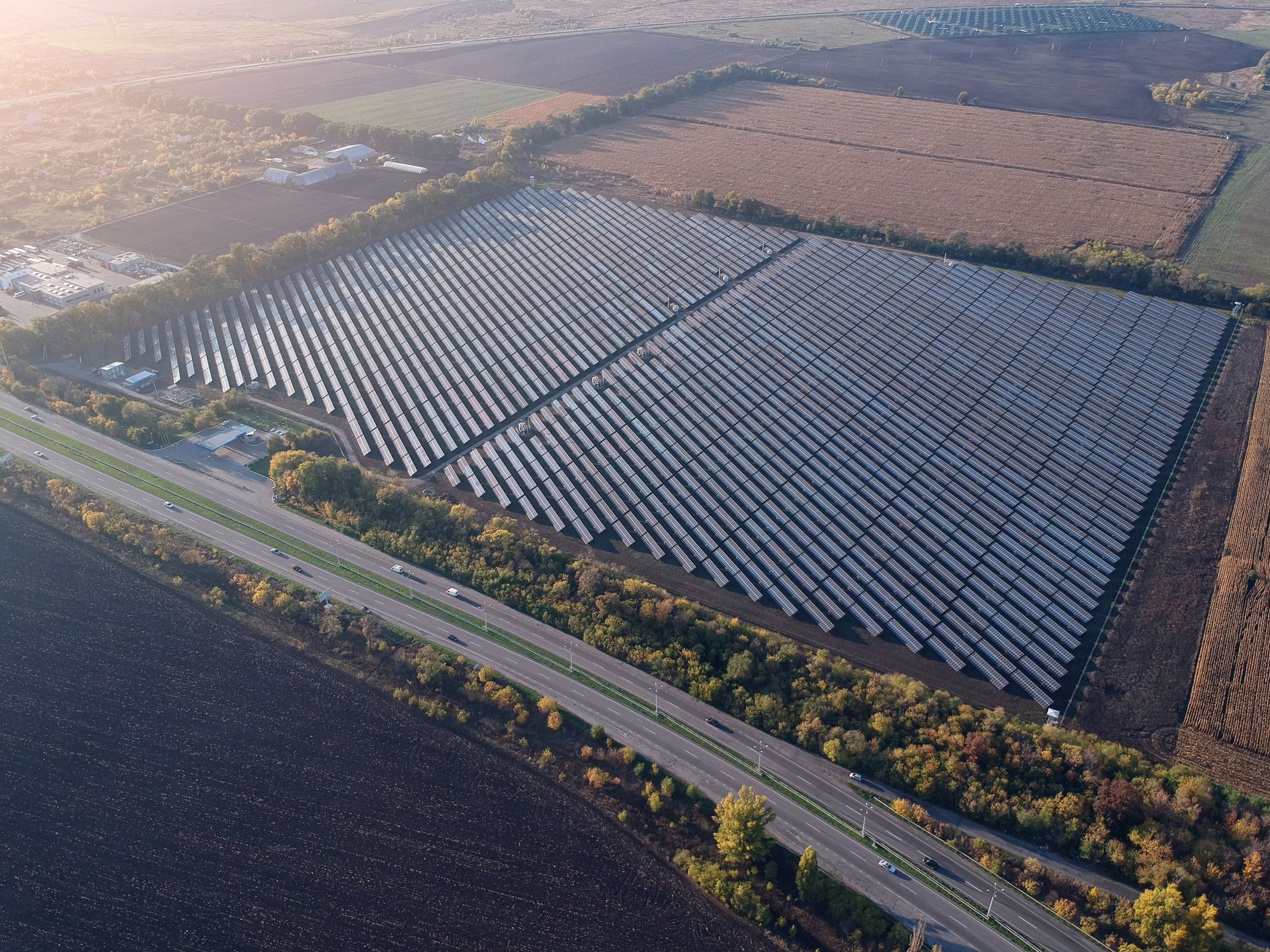 An aerial view of a solar farm beside a road and farmland