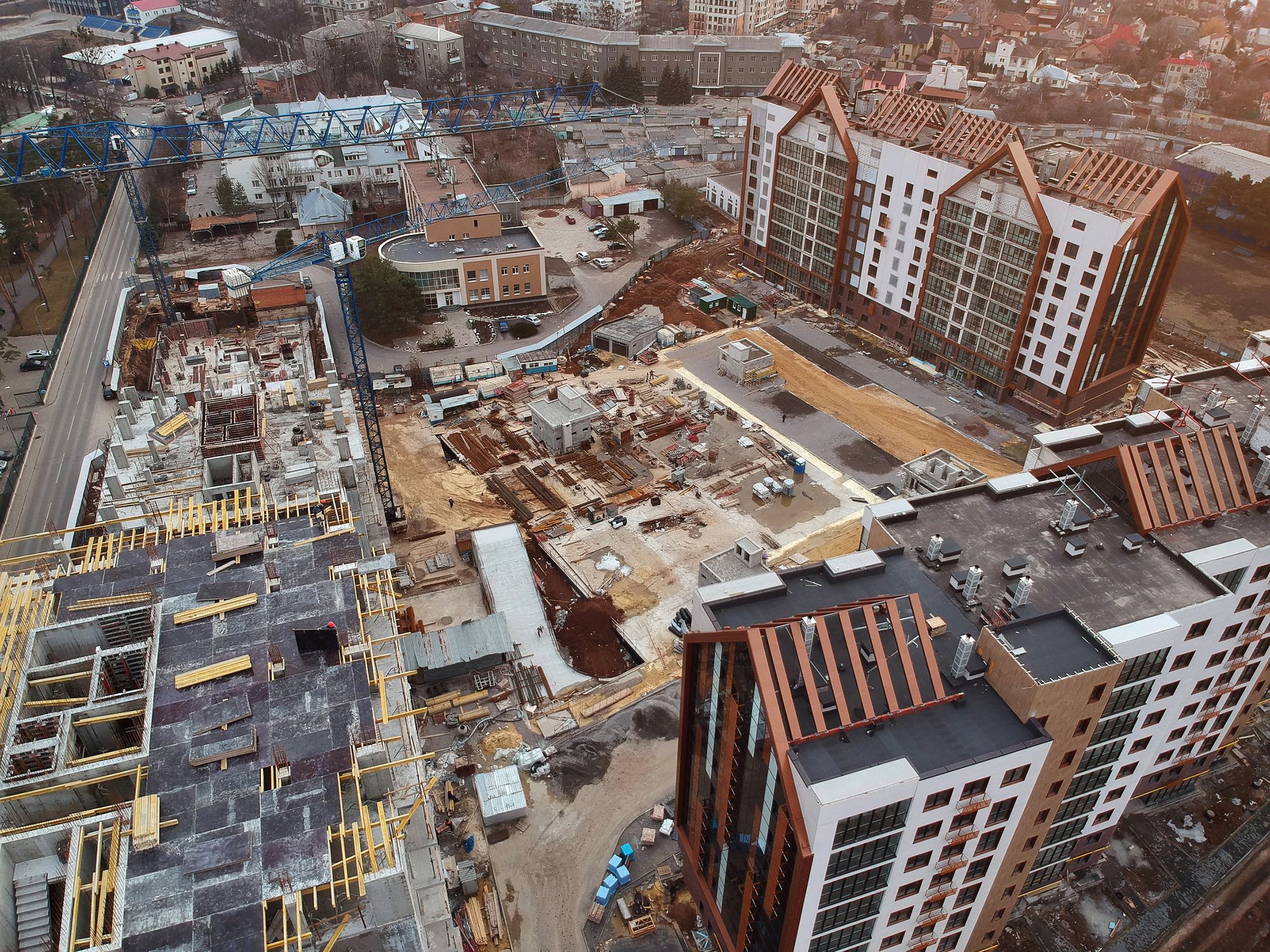 An aerial view of a building site with cranes between finished buildings
