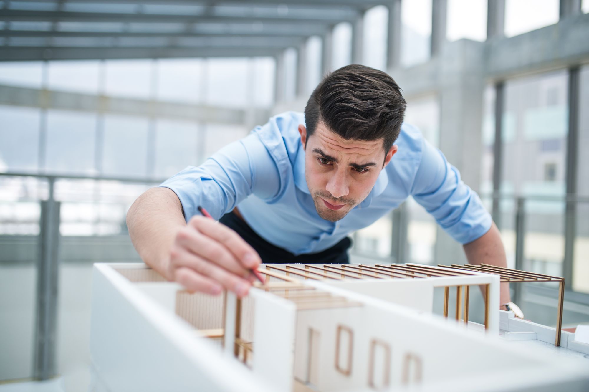 A person adjusting a physical model of a building on a desk